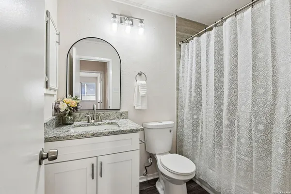 a bathroom with a granite countertop toilet sink and mirror