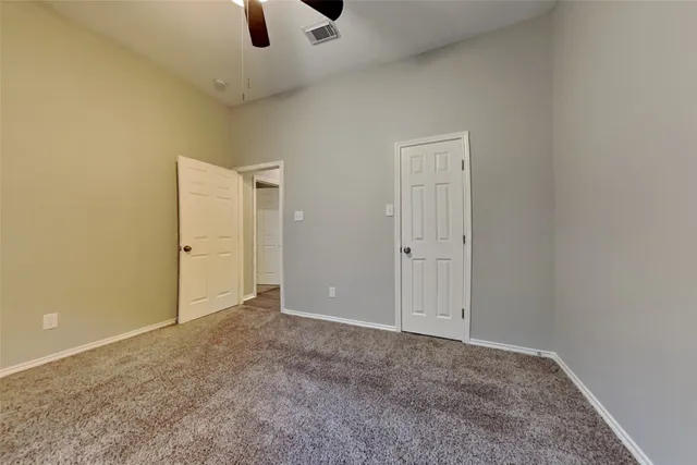 an empty room with ceiling fan and window