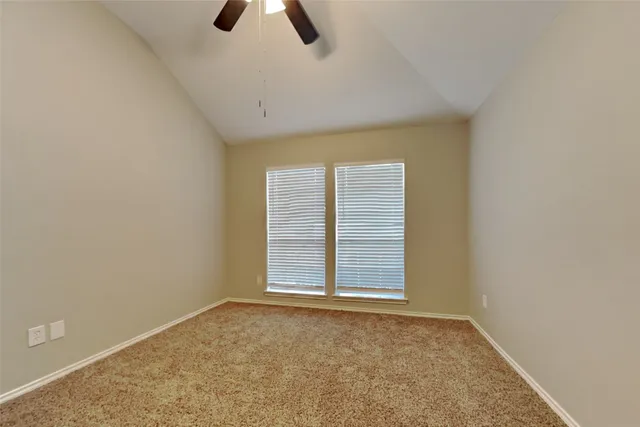 an empty room with ceiling fan and window