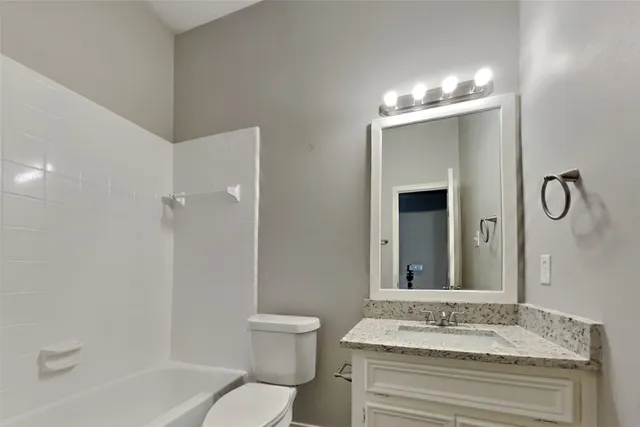 a bathroom with a granite countertop sink a toilet and shower