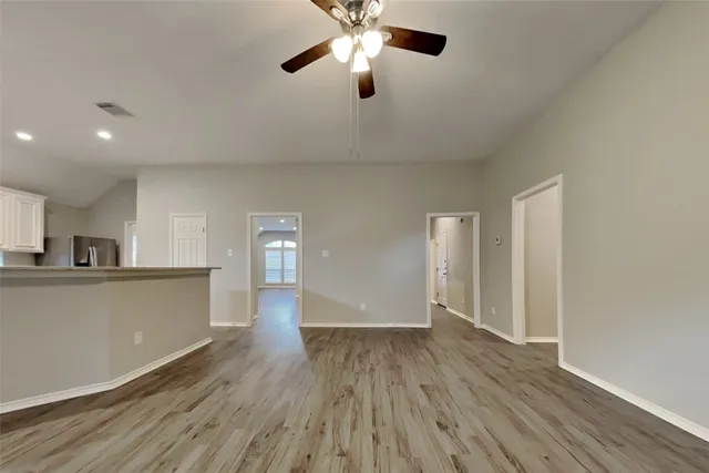 a view of empty room with wooden floor and fan