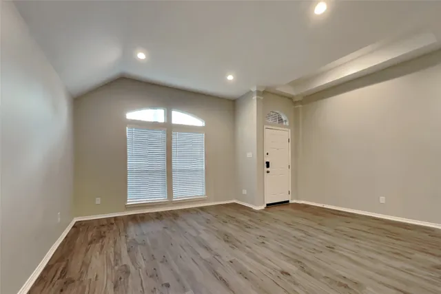 an empty room with wooden floor and windows