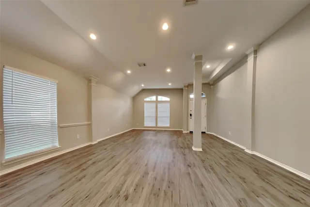 an empty room with wooden floor and windows