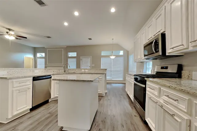 a kitchen with stainless steel appliances granite countertop a stove cabinets and wooden floor