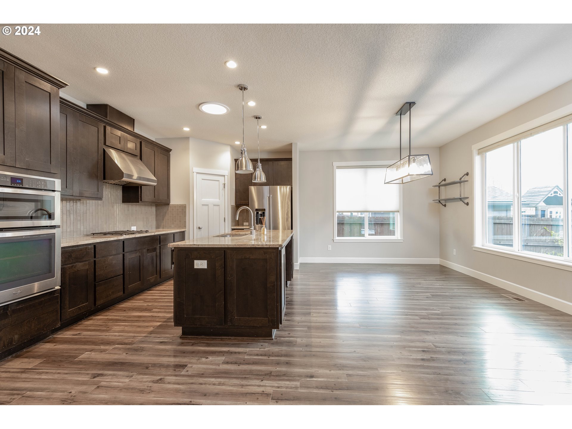 2714 Northeast 167th Circle Ridgefield, WA 98642 - Photo 7 of 35 a kitchen with stainless steel appliances kitchen island granite countertop a stove a sink dishwasher a refrigerator and a oven with wooden floor