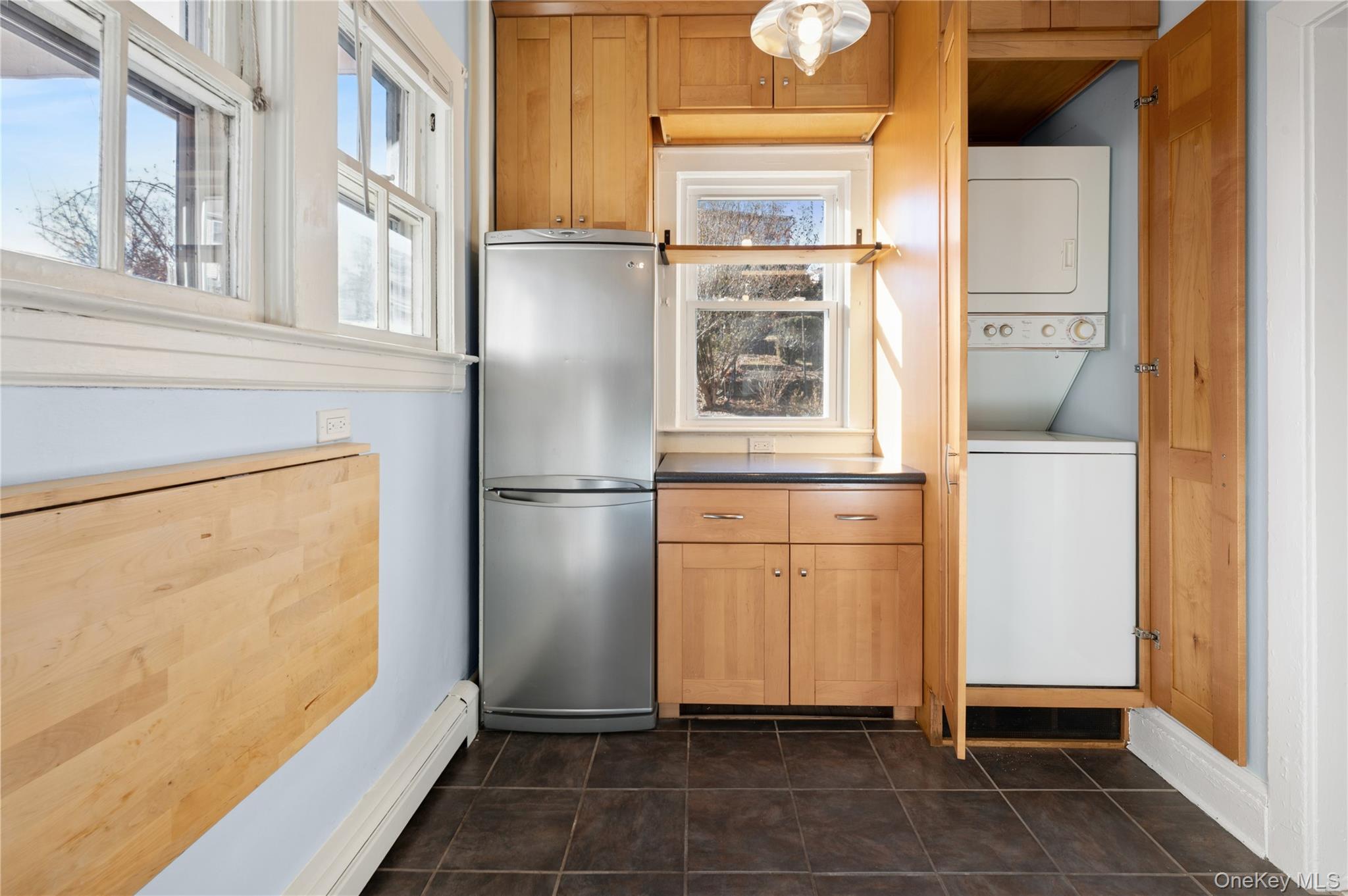 53 Allen Street, Unit 2 Dobbs Ferry, NY 10522 - Photo 12 of 28 Kitchen featuring freestanding refrigerator, a baseboard heating unit, stacked washer / dryer, dark countertops, and plenty of natural light