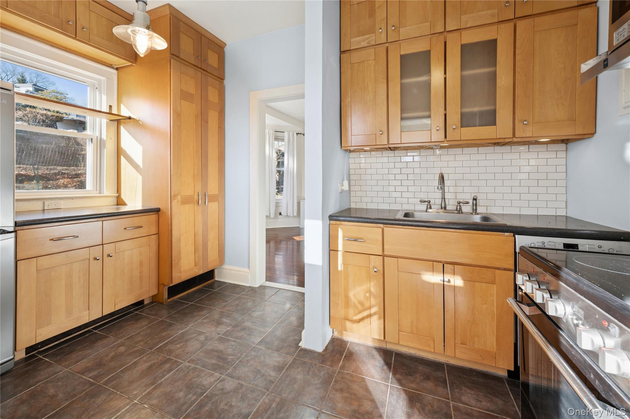 53 Allen Street, Unit 2 Dobbs Ferry, NY 10522 - Photo 10 of 28 Kitchen with stainless steel range with electric cooktop, decorative backsplash, glass insert cabinets, under cabinet range hood, and light brown cabinetry