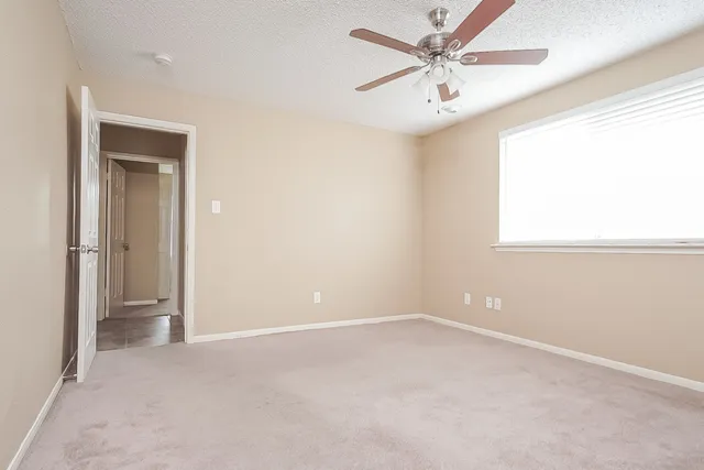 an empty room with a window and a fan