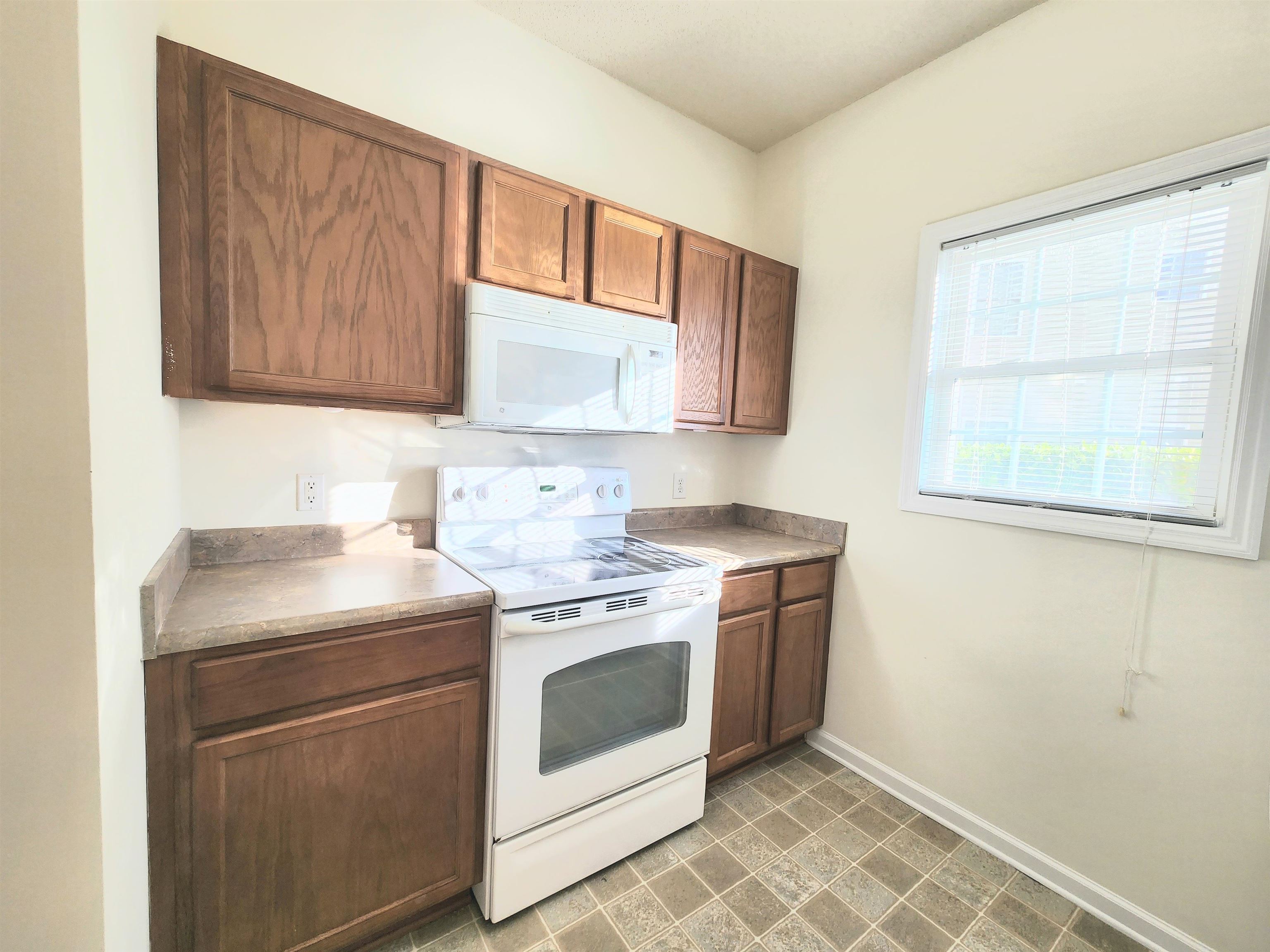 2080 Cross Gate Boulevard, Unit 105 Myrtle Beach, SC 29575 - Photo 14 of 25 Kitchen featuring white appliances, brown cabinetry, and light countertops