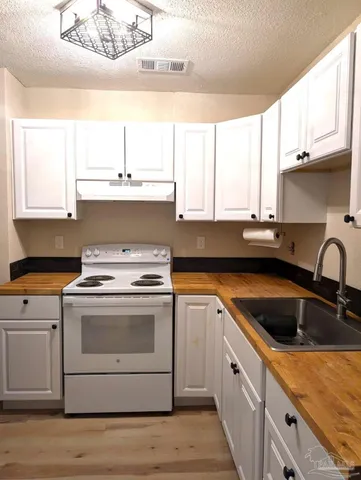 a kitchen with granite countertop a sink a stove and cabinets