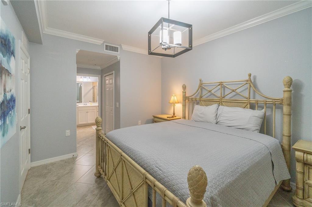 9590 Trevi Court, Unit 5317 Naples, FL 34113 - Photo 13 of 38 a bedroom with a bed and a chandelier
