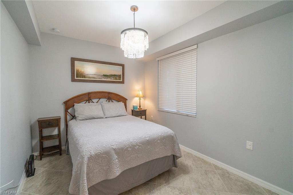 9590 Trevi Court, Unit 5317 Naples, FL 34113 - Photo 16 of 38 a bedroom with a bed and a chandelier