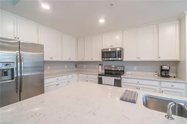 a kitchen with stainless steel appliances granite countertop a refrigerator sink and stove