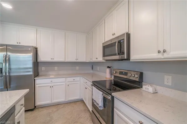a kitchen with granite countertop white cabinets and stainless steel appliances