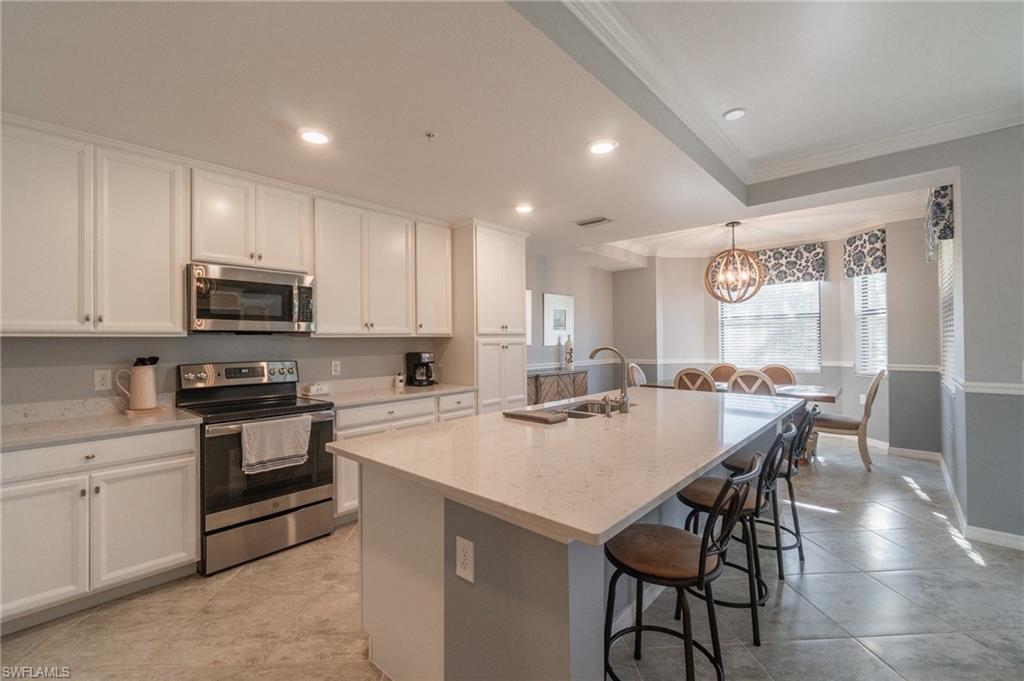 9590 Trevi Court, Unit 5317 Naples, FL 34113 - Photo 10 of 38 a kitchen with a stove a sink and a microwave