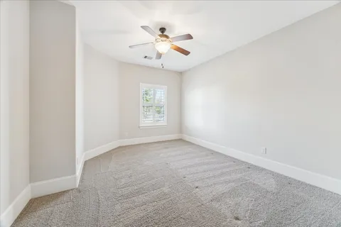an empty room with windows and ceiling fan
