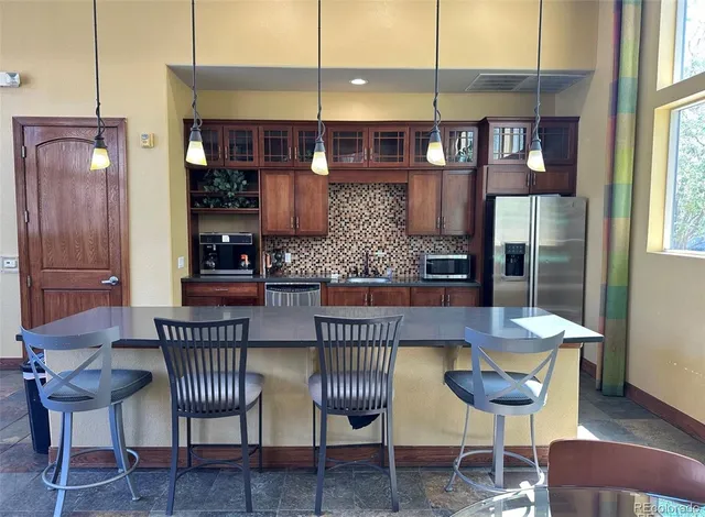 a kitchen with stainless steel appliances granite countertop a table chairs and a wooden floor