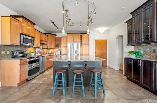 a kitchen with stainless steel appliances granite countertop a stove top oven a refrigerator a stove top oven and a dining table with wooden floor