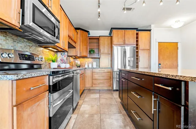a kitchen with stainless steel appliances granite countertop a stove a sink and a refrigerator