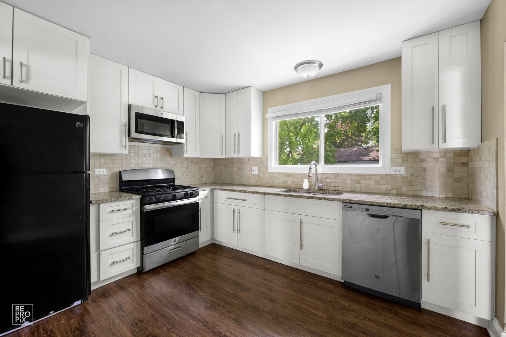 48 Pheasant Road Matteson, IL 60443 - Photo 11 of 23 a kitchen with granite countertop white cabinets a window and stainless steel appliances