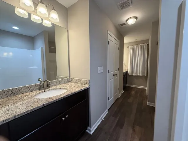 a bathroom with a granite countertop sink a large mirror and a shower