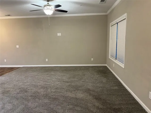 an empty room with a chandelier fan and windows