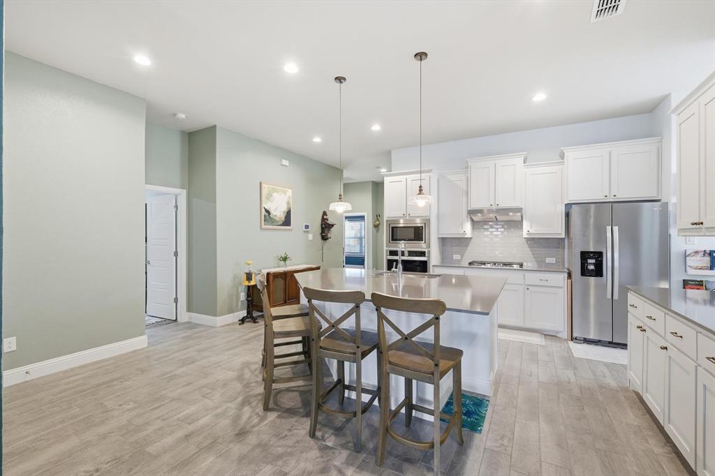 2213 Ruff Road Denton, TX 76205 - Photo 15 of 40 a kitchen with stainless steel appliances a refrigerator a stove a sink dishwasher and a dining table with wooden floor
