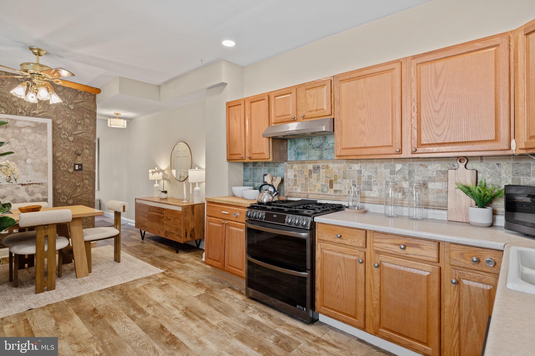 4092 Pechin Street Philadelphia, PA 19128 - Photo 7 of 28 a kitchen with stainless steel appliances granite countertop a stove a sink dishwasher and white cabinets with wooden floor