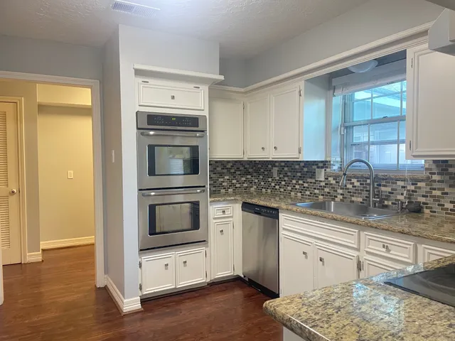a kitchen with granite countertop a stove and a sink