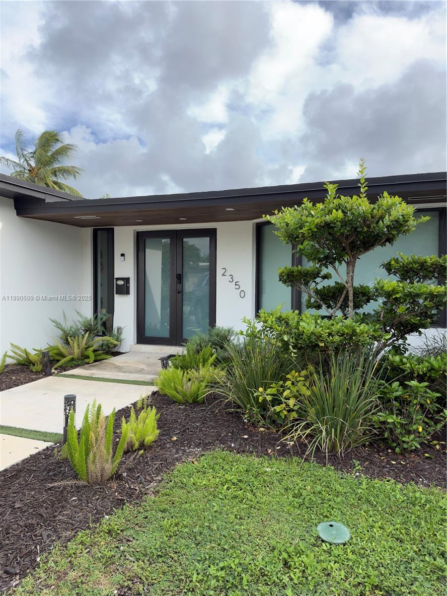 2350 Northeast 194th Street Miami, FL 33180 - Photo 1 of 24 a front view of a house with a garden