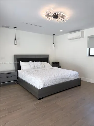a bedroom with a bed ceiling fan and wooden floor