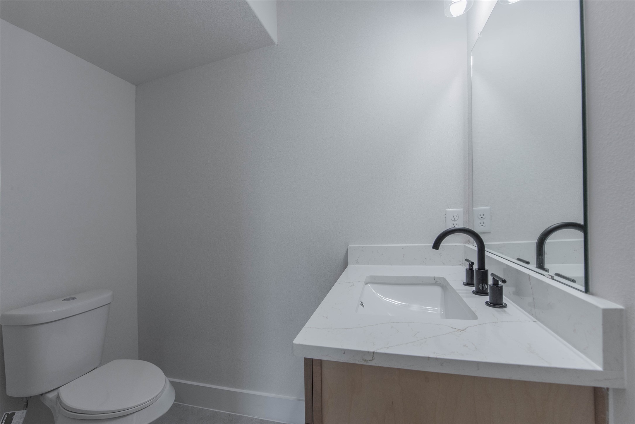 9311 Jutland Road Houston, TX 77033 - Photo 8 of 28 The powder room is conveniently located just off the living room and features quartz countertops and a stylish vanity, offering a bright and functional space.