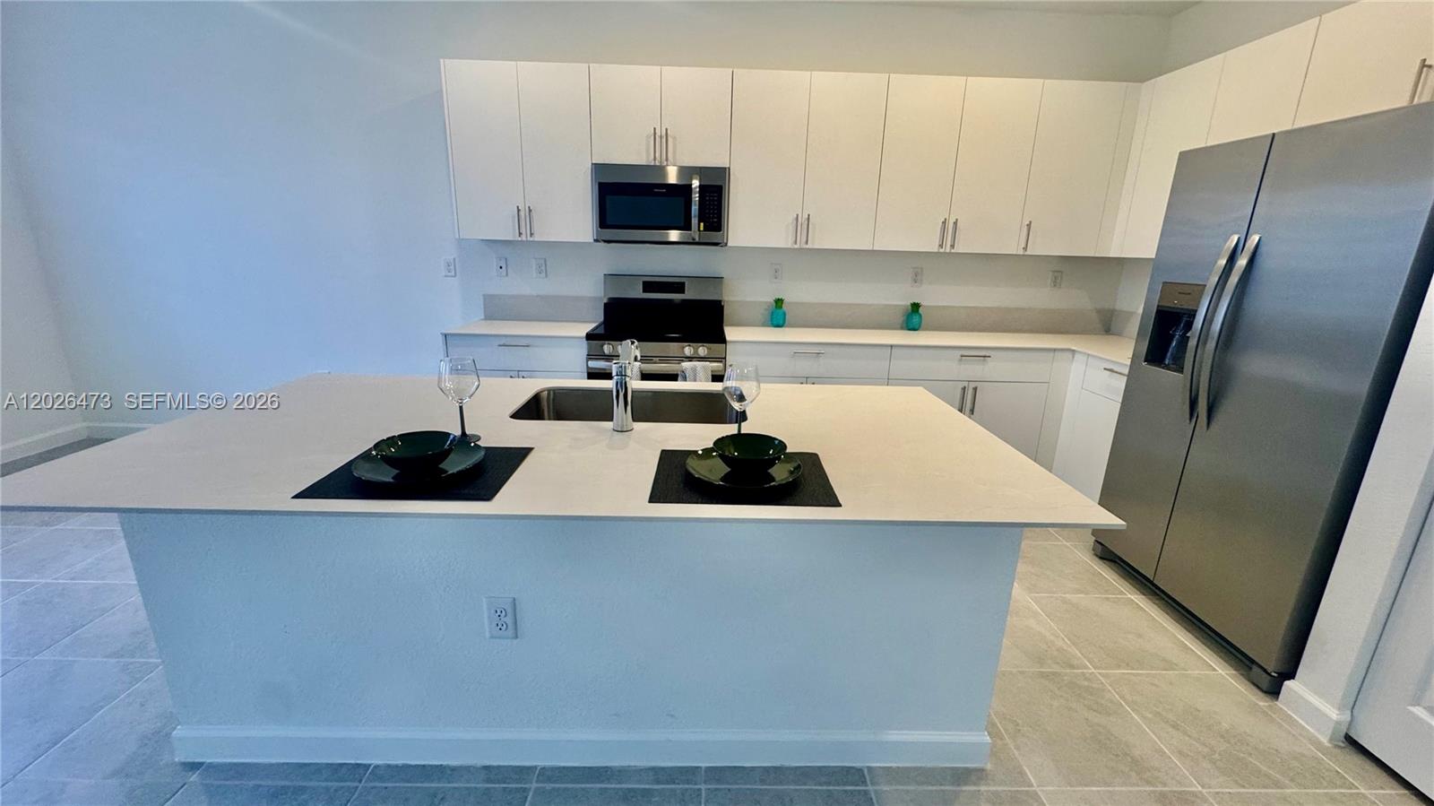 19479 Southwest 340th Street, Unit 1 Homestead, FL 33034 - Photo 42 of 58 a kitchen with stainless steel appliances a refrigerator stove a sink and white cabinets