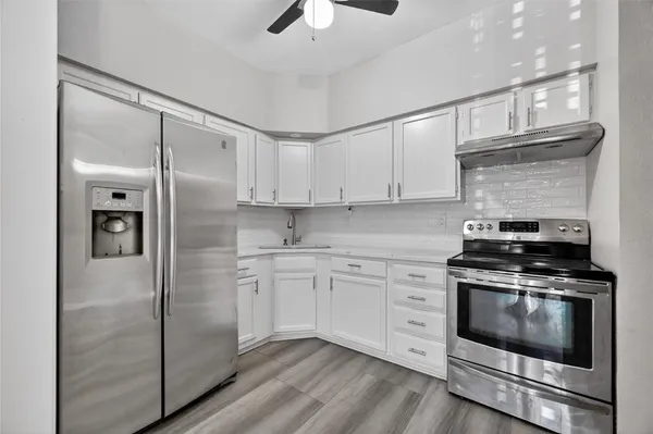 a kitchen with stainless steel appliances granite countertop a stove a refrigerator and a white cabinets
