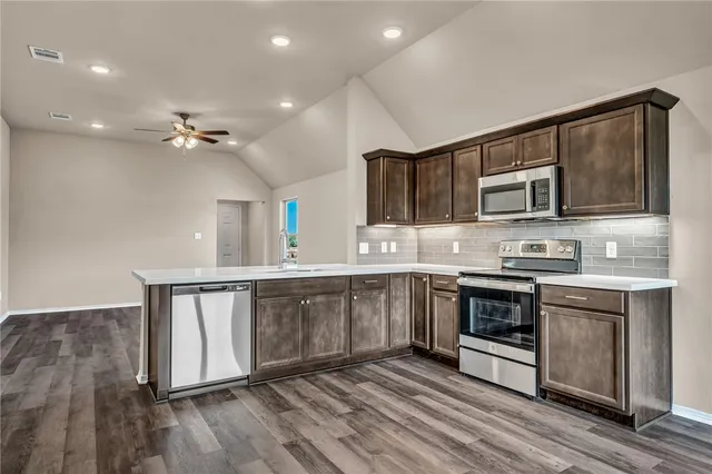a kitchen with stainless steel appliances granite countertop a stove a sink and a microwave