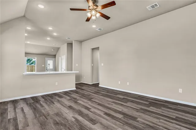 a view of an empty room with window and wooden floor