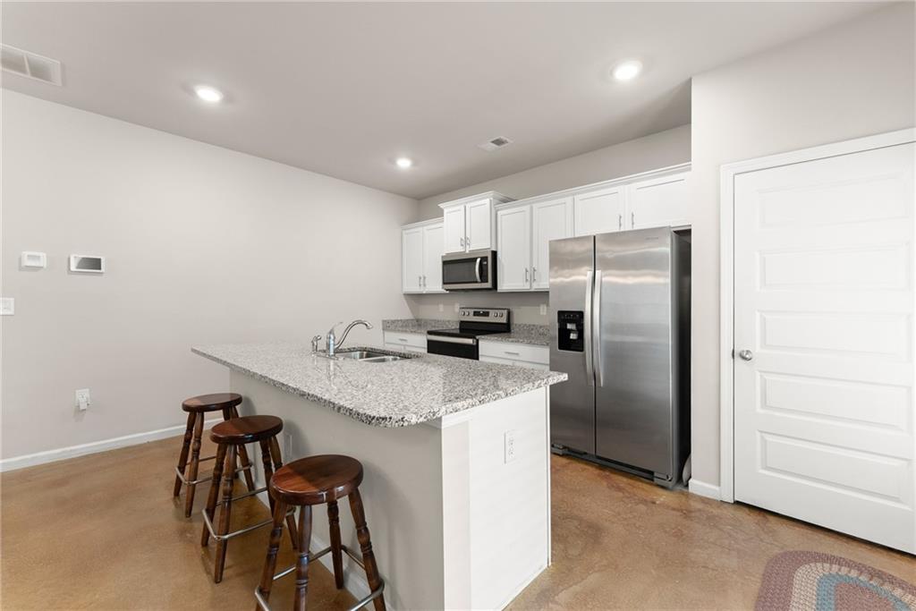 63 Conroe Court Hoschton, GA 30548 - Photo 13 of 44 a kitchen with kitchen island a refrigerator stove and microwave