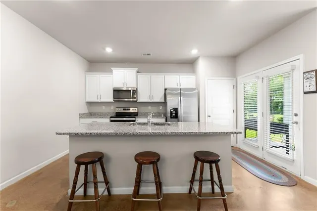 a kitchen with stainless steel appliances granite countertop a stove top oven a sink a dining table and chairs
