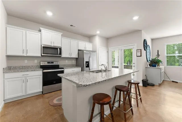 a kitchen with stainless steel appliances granite countertop a stove a sink a microwave a dining table and chairs