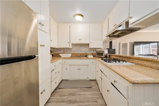 a large white kitchen with stainless steel appliances granite countertop a stove a sink dishwasher and a refrigerator