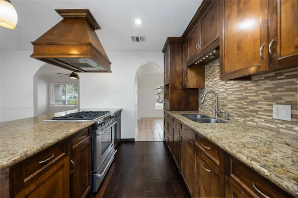 a kitchen with stainless steel appliances granite countertop a sink a stove and a wooden floors