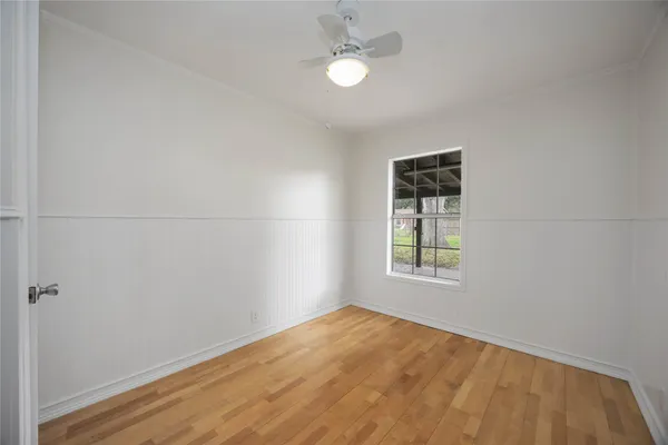 an empty room with a window and ceiling fan