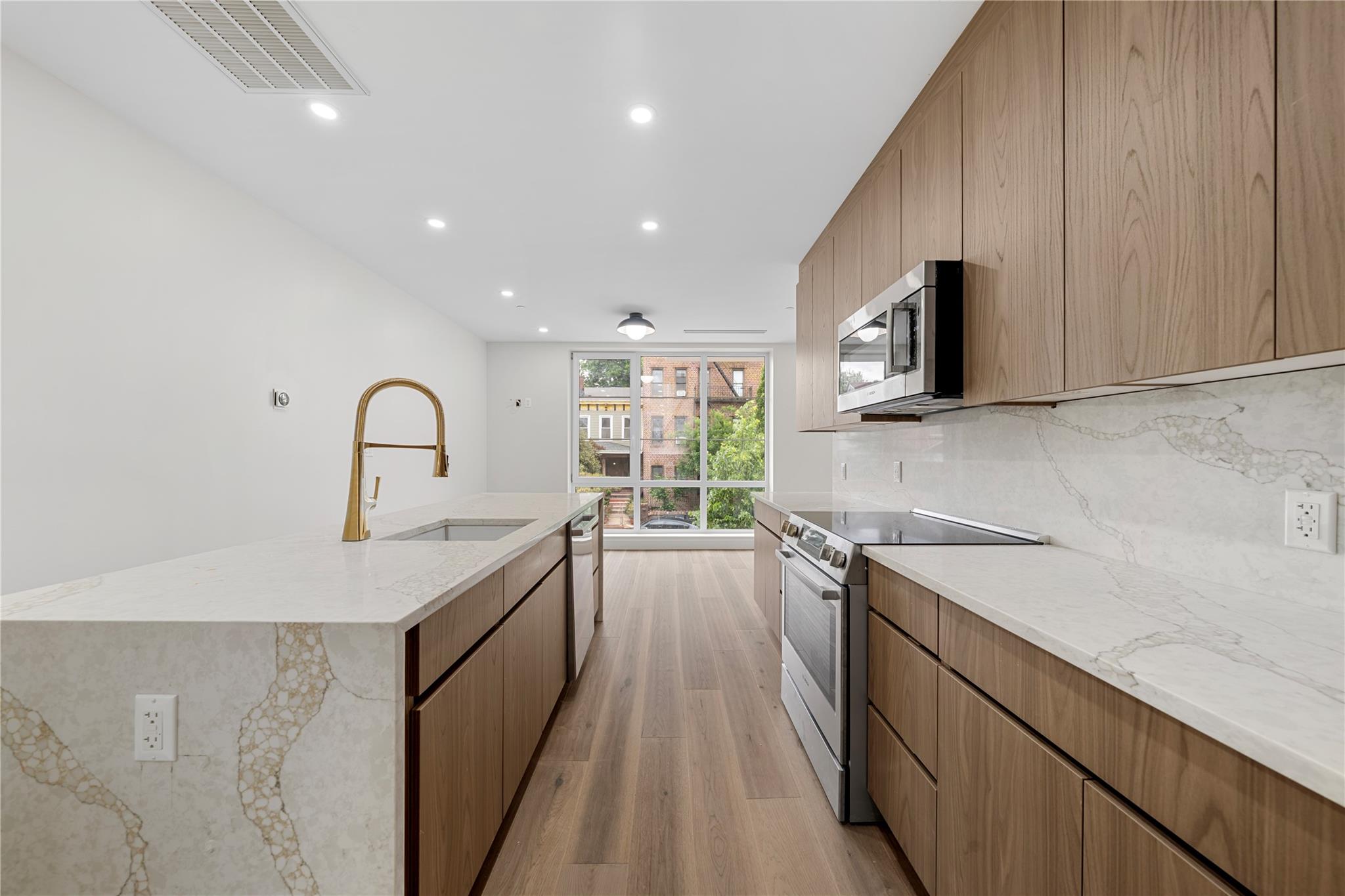 312 Fenimore Street Brooklyn, NY 11225 - Photo 14 of 37 Kitchen featuring stainless steel appliances, a sink, light wood finished floors, tasteful backsplash, and light stone countertops