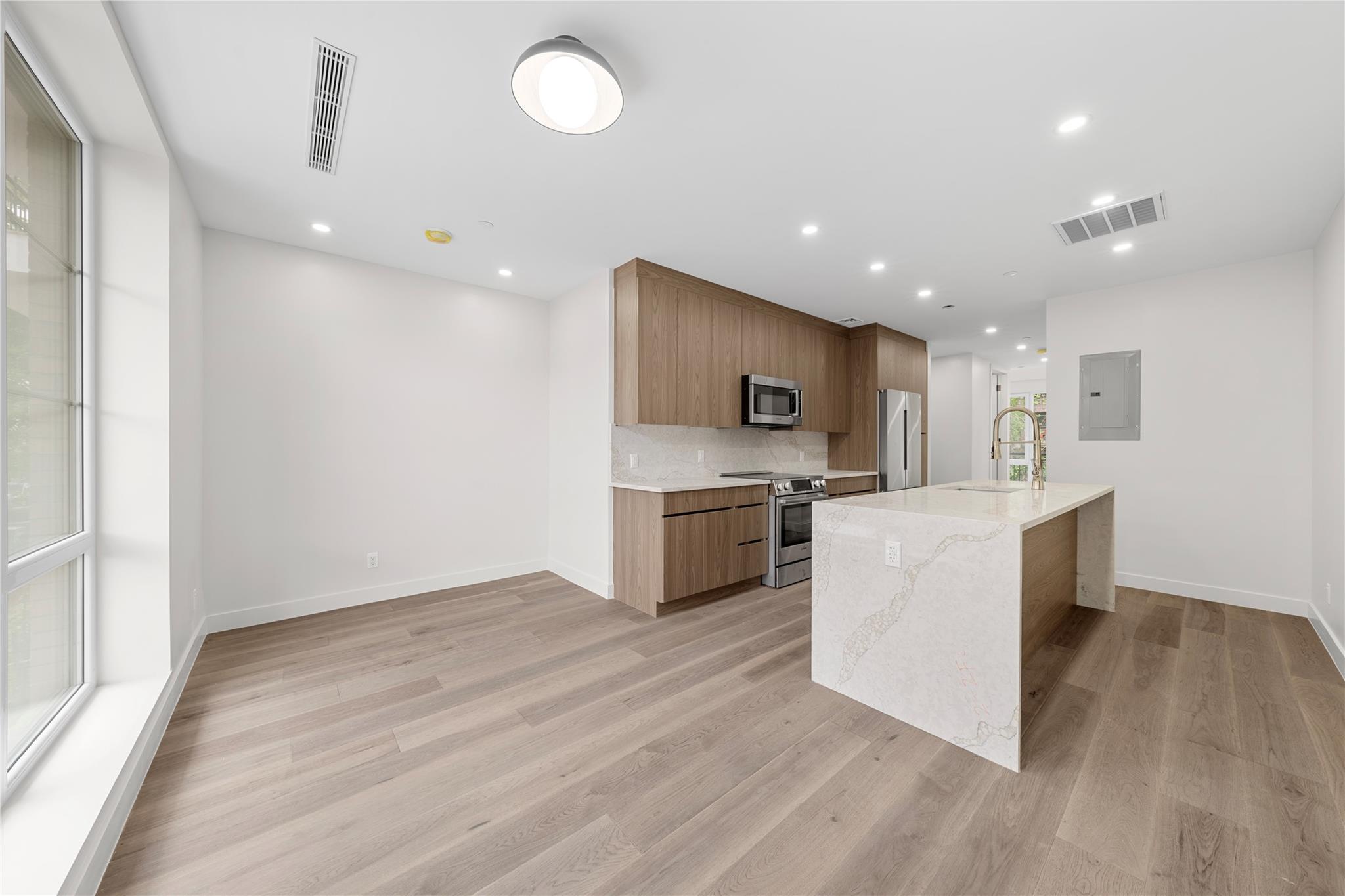 312 Fenimore Street Brooklyn, NY 11225 - Photo 15 of 37 Kitchen featuring stainless steel appliances, electric panel, a sink, backsplash, and light wood-style floors