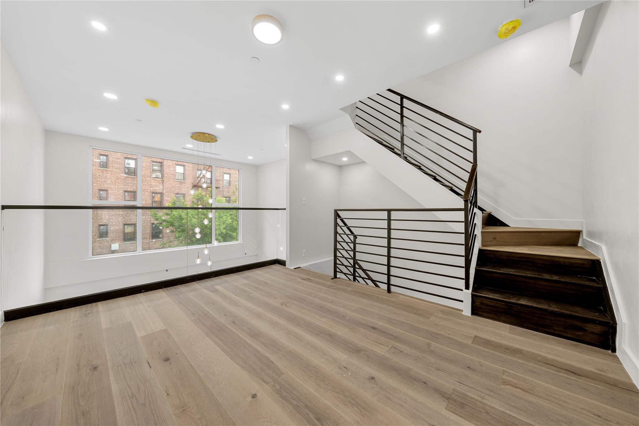 312 Fenimore Street Brooklyn, NY 11225 - Photo 16 of 37 Unfurnished living room with wood finished floors, baseboards, recessed lighting, and stairs