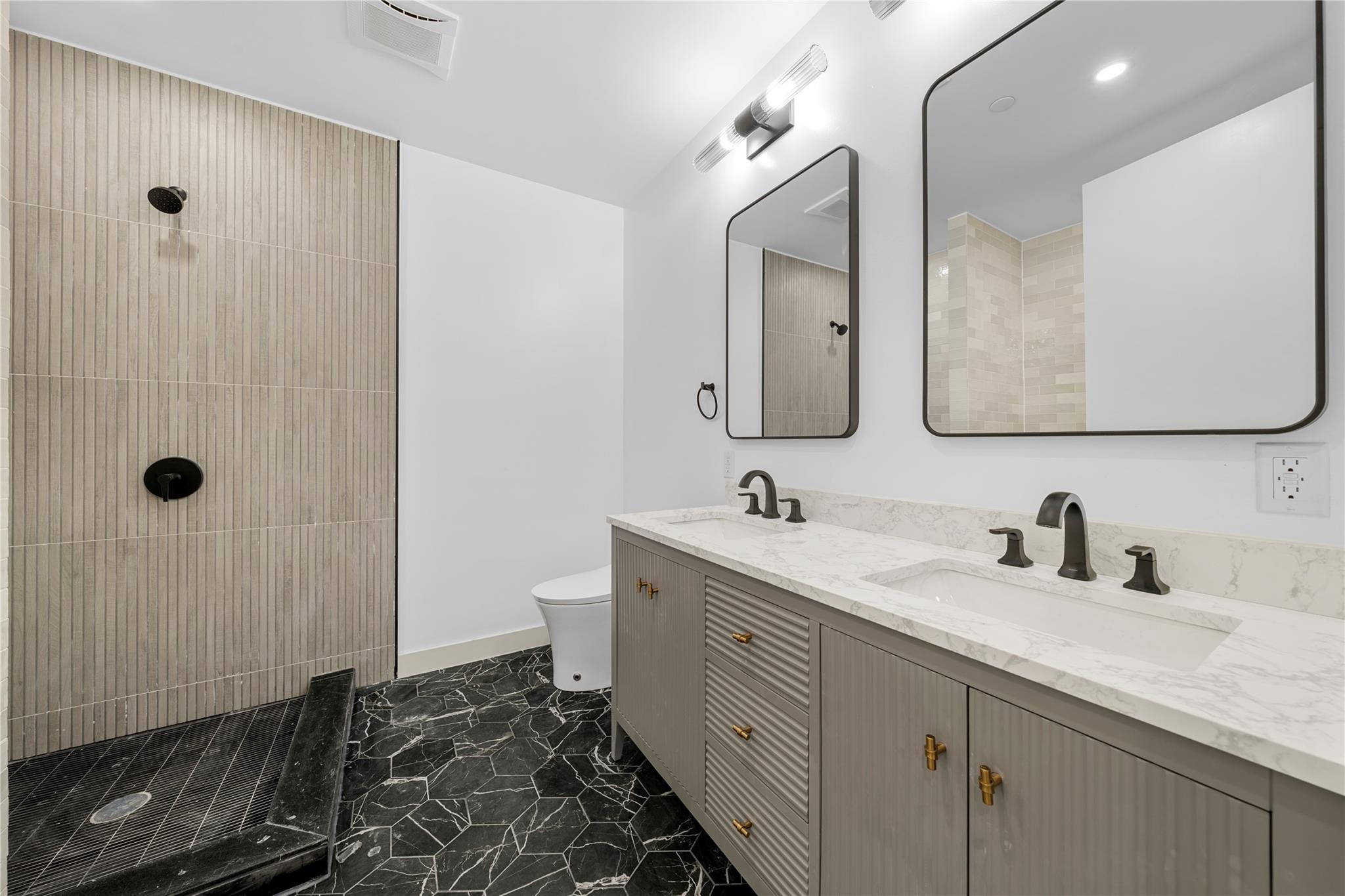 312 Fenimore Street Brooklyn, NY 11225 - Photo 18 of 37 Full bath featuring marble look tile flooring, tiled shower, toilet, double vanity, and baseboards