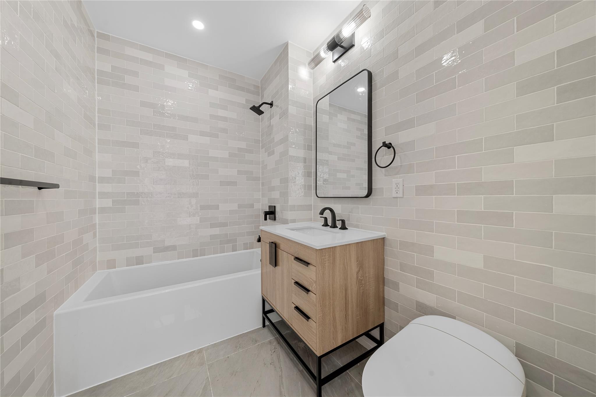 312 Fenimore Street Brooklyn, NY 11225 - Photo 24 of 37 Bathroom featuring tile walls, vanity, toilet, and shower / bathtub combination