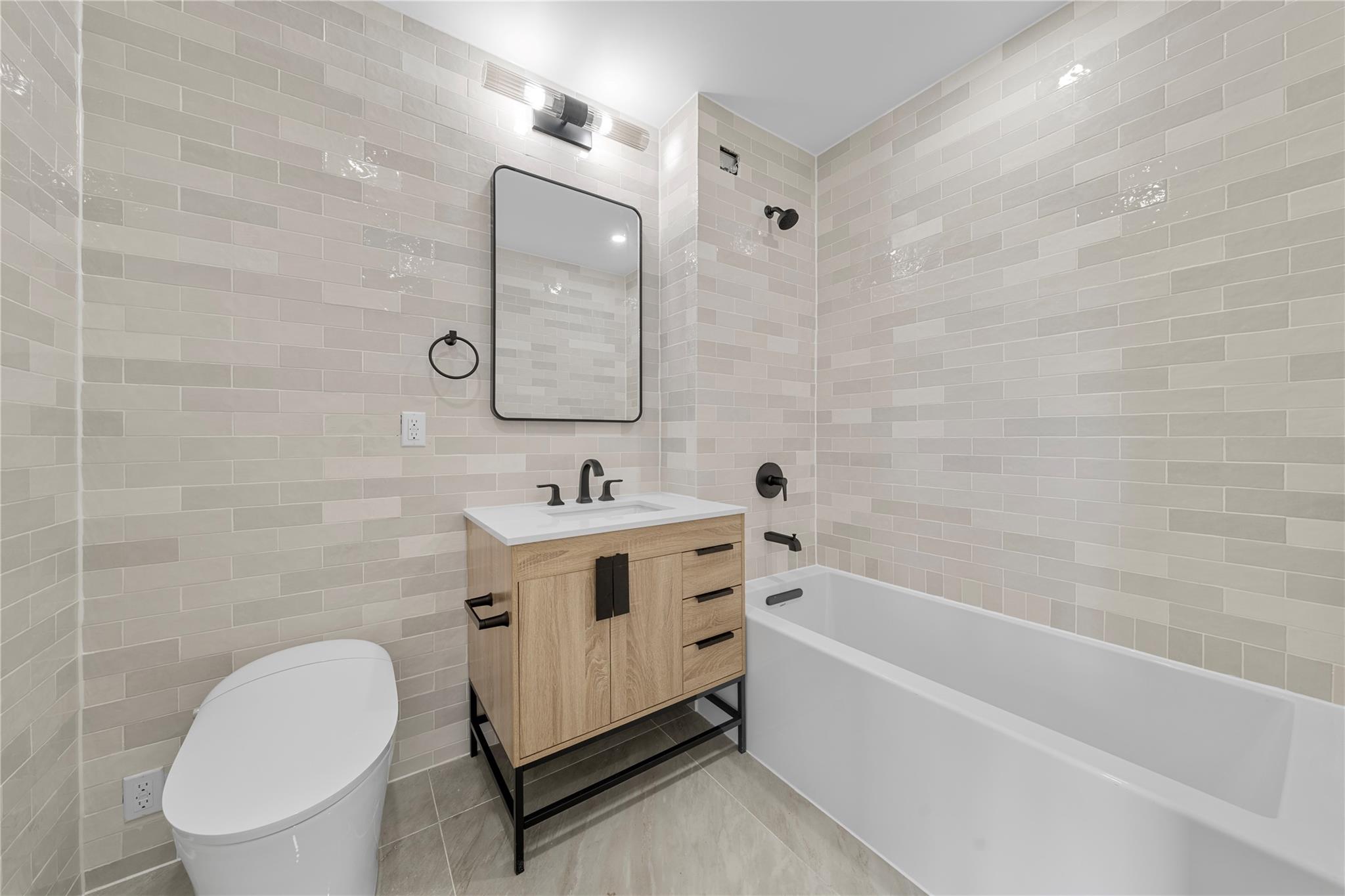312 Fenimore Street Brooklyn, NY 11225 - Photo 29 of 37 Full bath featuring tile walls, vanity, toilet, bathtub / shower combination, and tile patterned floors