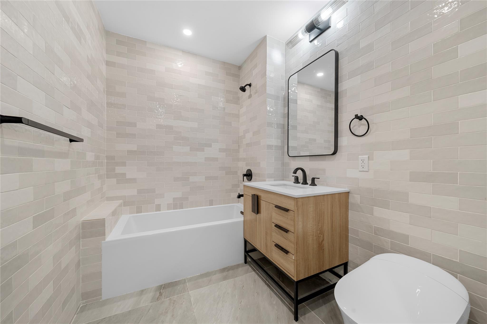 312 Fenimore Street Brooklyn, NY 11225 - Photo 8 of 37 Full bath with tile walls, vanity, shower / washtub combination, toilet, and tile patterned floors