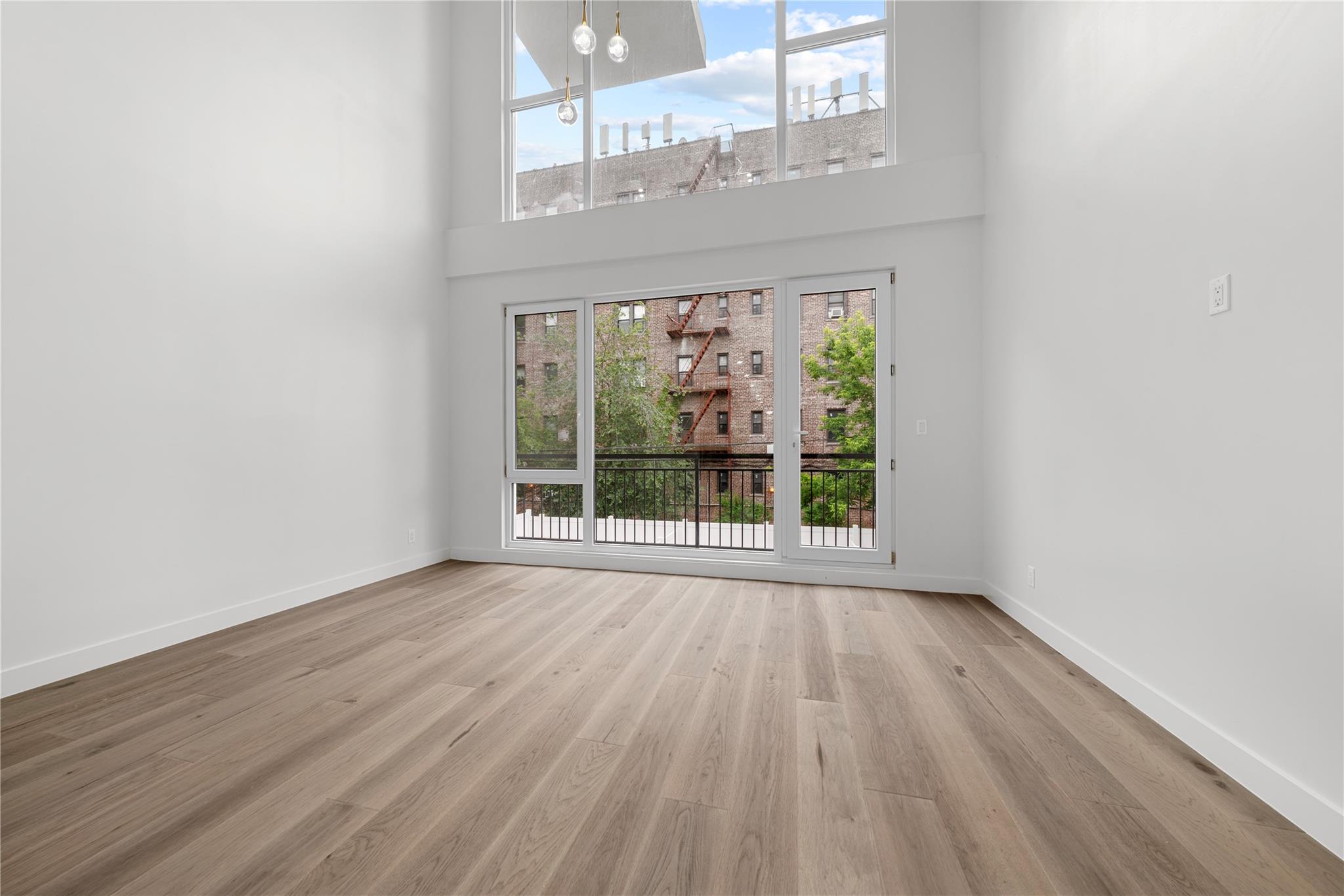 312 Fenimore Street Brooklyn, NY 11225 - Photo 10 of 37 Unfurnished living room featuring a towering ceiling, light wood-style flooring, baseboards, and a chandelier